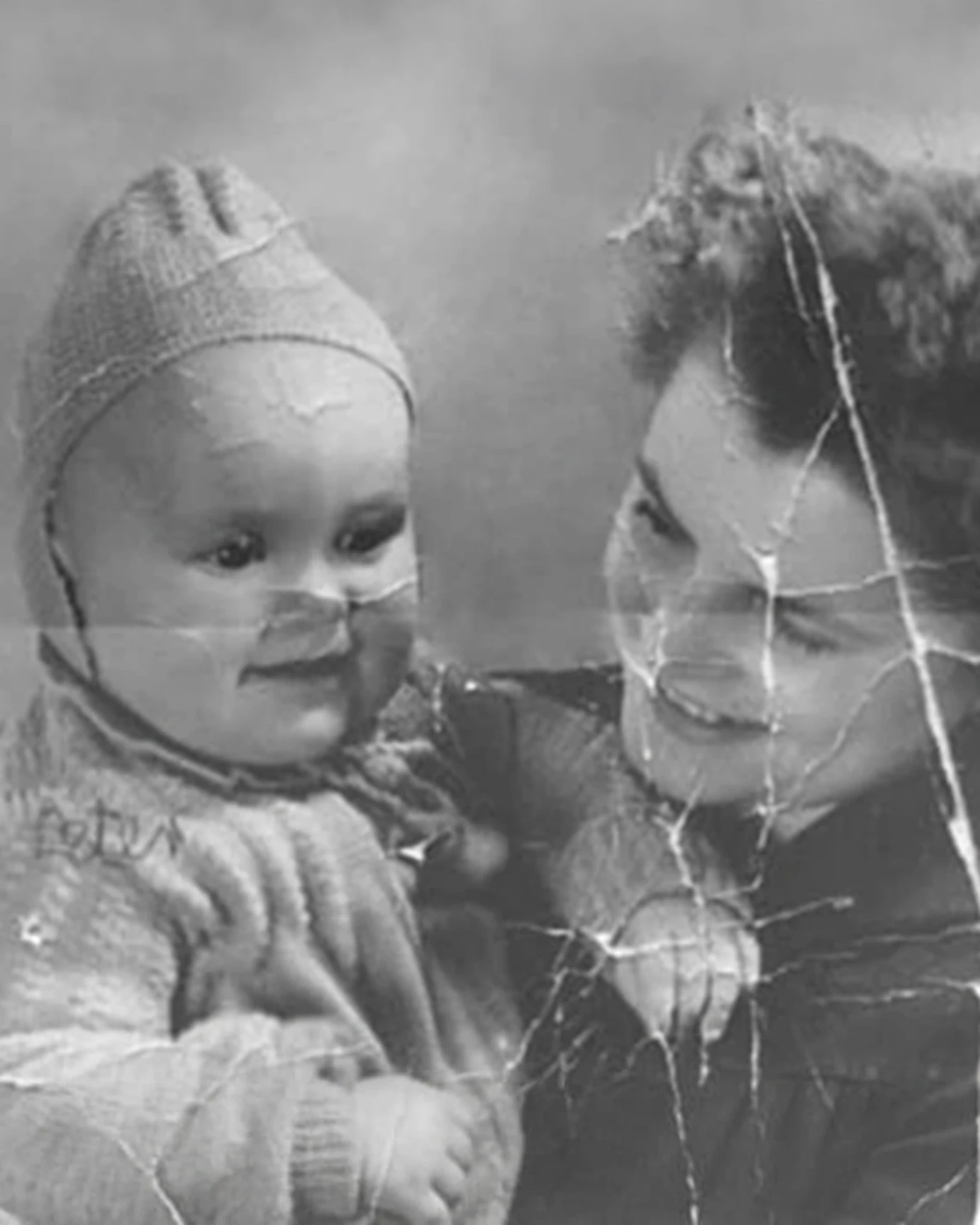 Scratched black and white photo of mother holding baby before repair